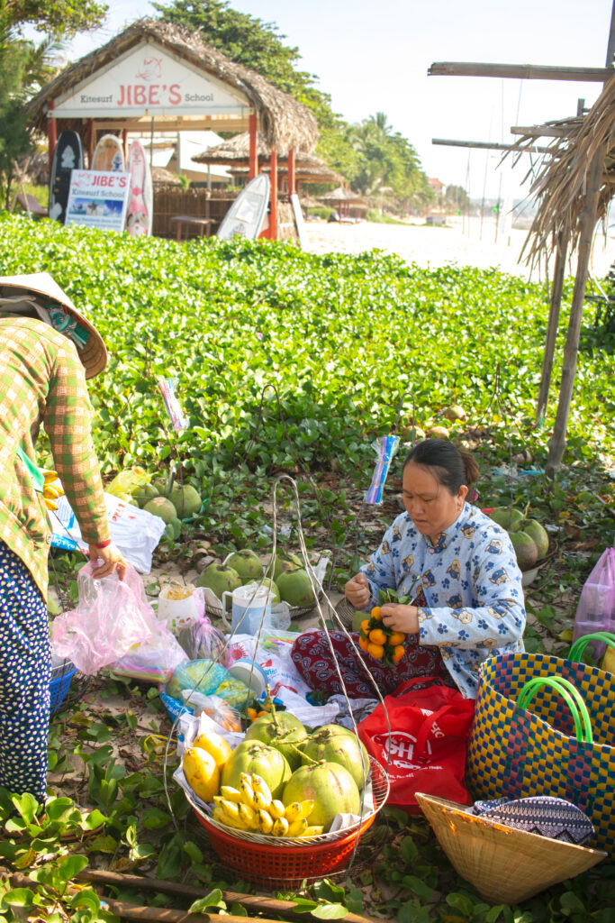 women in vietnam selling fruit on the beach